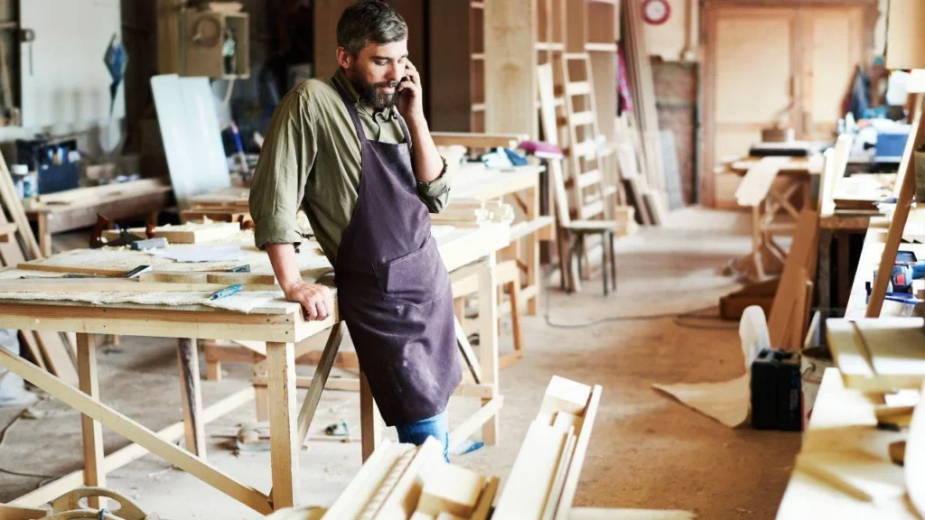 menuisier au téléphone dans un chantier